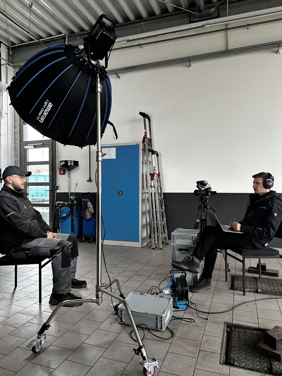 Interview mit einem Mitarbeiter in der Werkstatthalle von Reifen Wagner, Kamera und Licht im Vordergrund