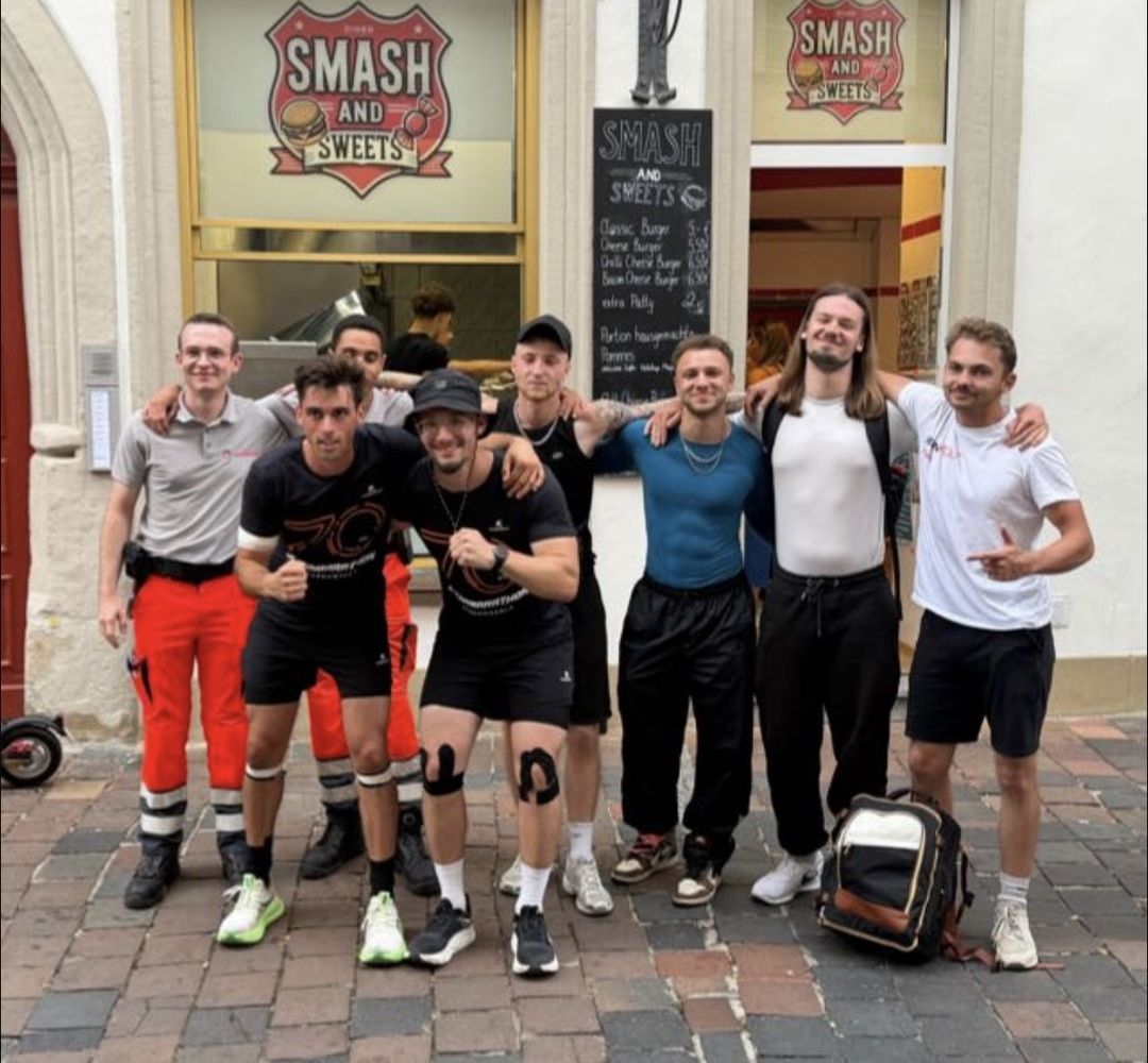 Gruppenfoto nach dem 70-Kilometer-Spendenlauf für das Sternenzelt Bamberg: die beiden Läufer in schwarzen Shirts mit der Zahl 70, umgeben von Begleitern und zwei Sanitätern